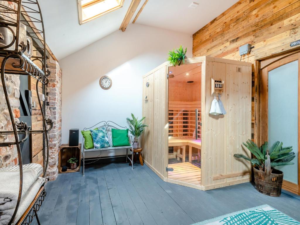 a room with a large wooden cabinet and a chair at Bockety Barn in Stalham