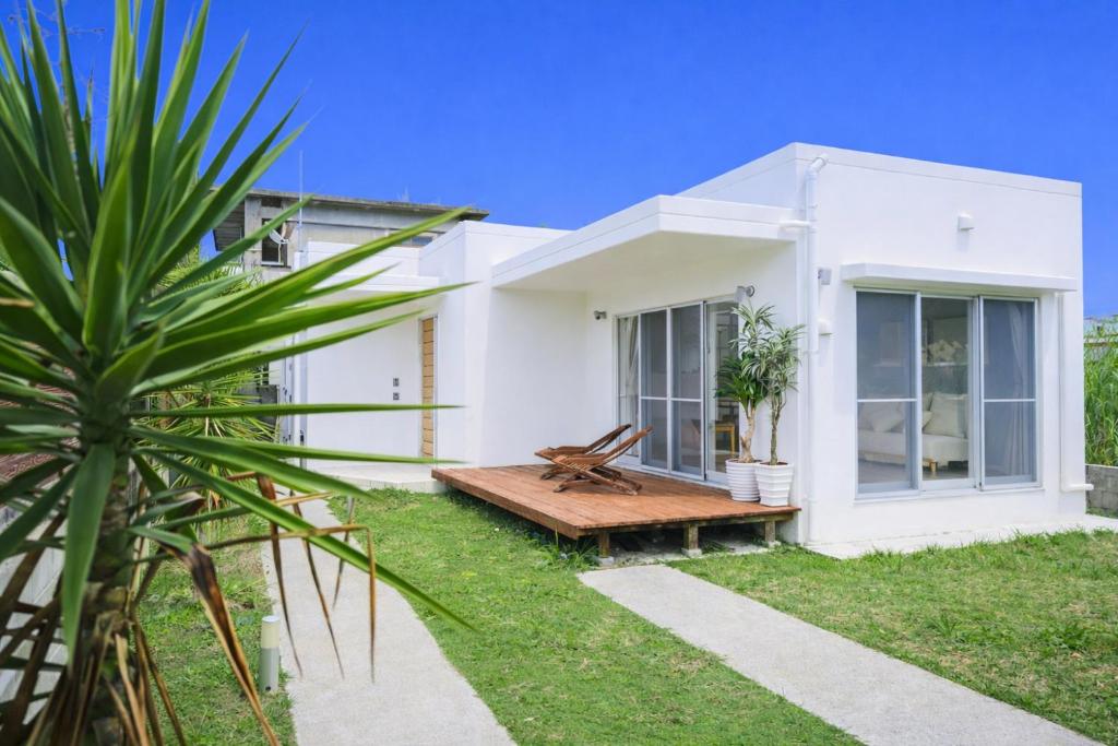 a white house with a bench in the yard at Third Place Onna Tancha Villa in Onna