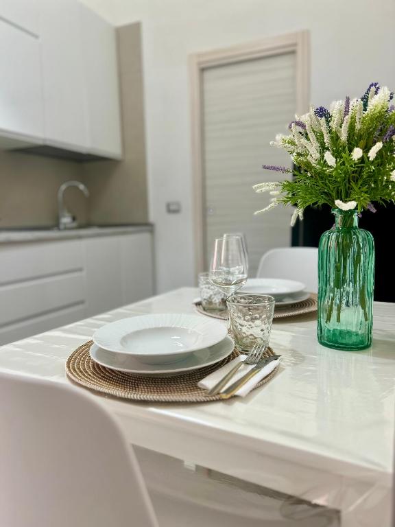 a table with plates and glasses and a vase of flowers at Sweet Home in Vico Equense