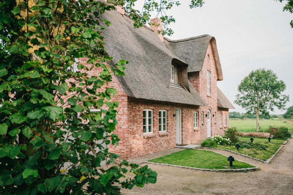 an old brick house with a gray roof at Ferring Neest in Midlum