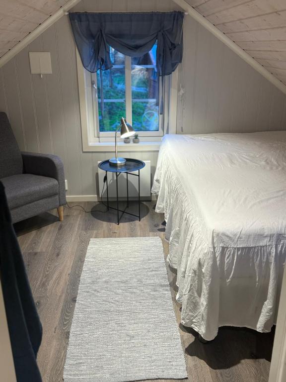a bedroom with a bed and a chair and a window at Rosenli Gård in Tønsberg