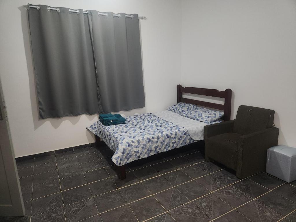 a small bedroom with a bed and a curtain at Xaveco hospedagem in Mangaratiba