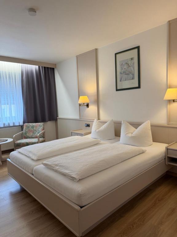 a hotel room with a large bed and a chair at Niederalteicher Hof in Hengersberg