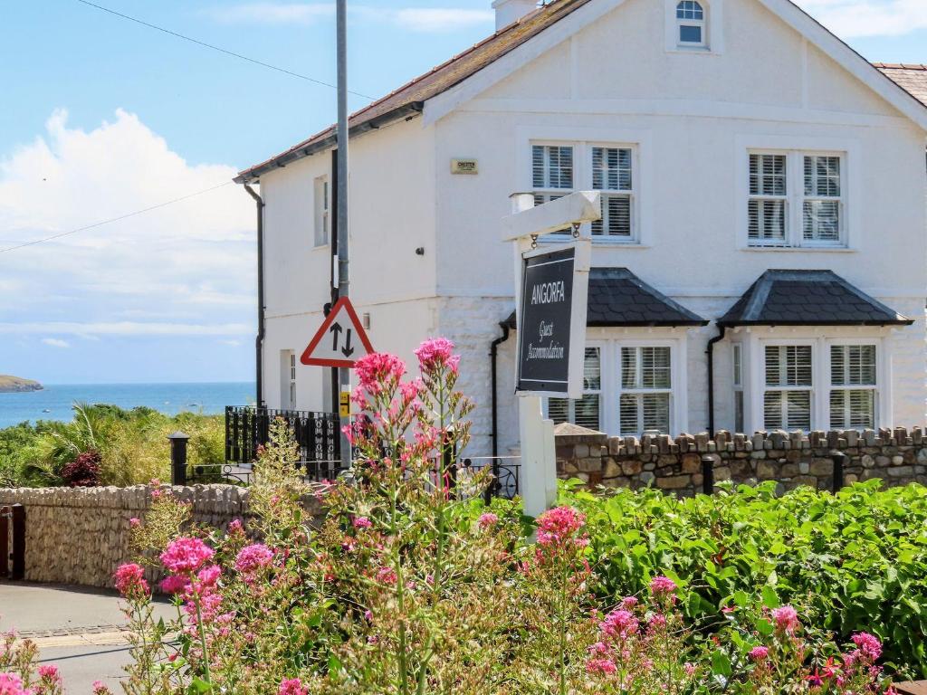 a white house with flowers in front of it at Angorfa Apartment in Pwllheli