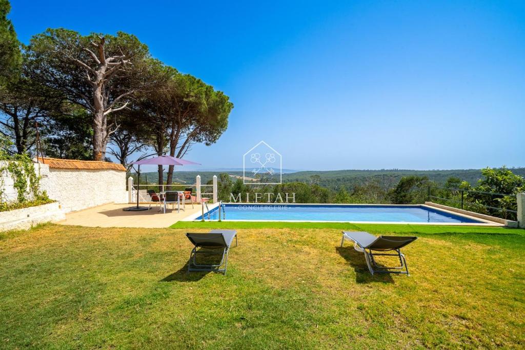 a swimming pool with two chairs in the grass at Charming villa with pool and unobstructed view in Tangier