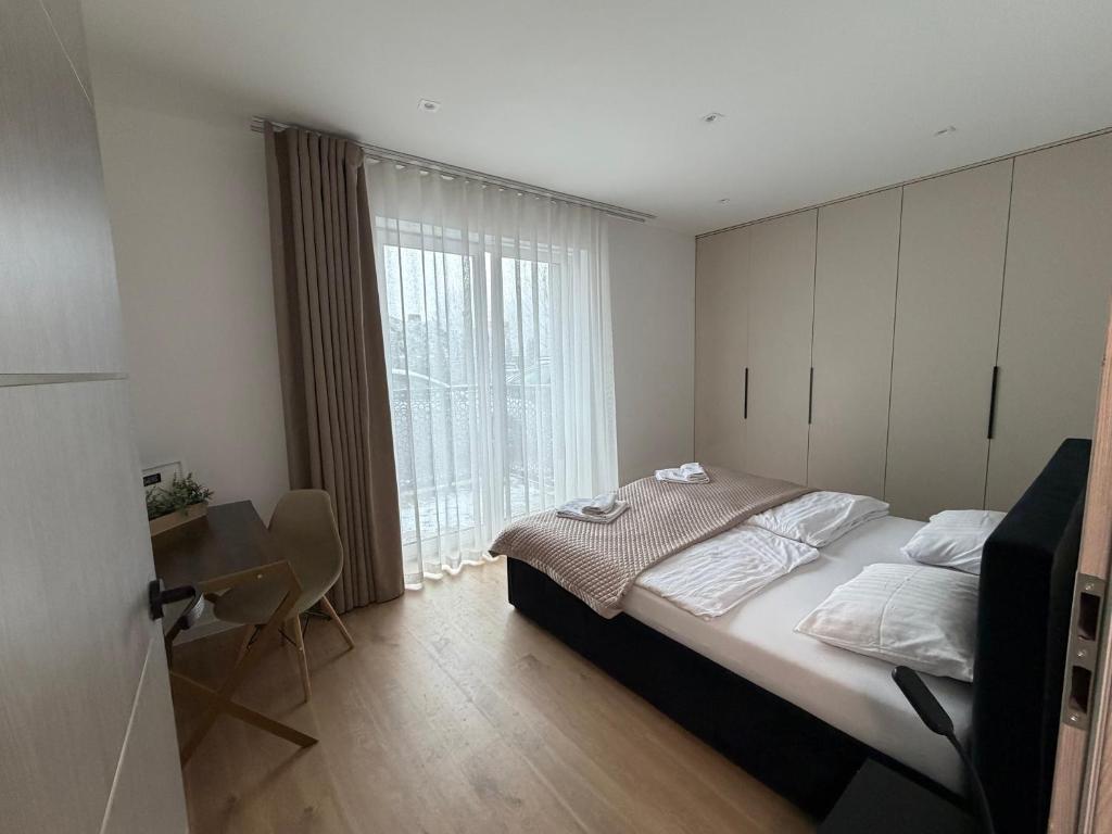 a bedroom with a bed and a desk and a window at Duży Apartament 3 pokoje Park City in Ostrów Wielkopolski