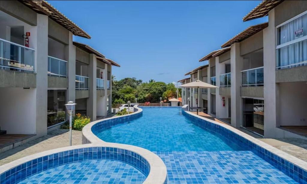 a swimming pool in the middle of two buildings at Village com 2 suites com ar a 300mts da praia e do rio in Mata de Sao Joao