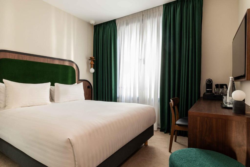 a hotel room with a bed and a green curtain at Hotel Le Richemont in Paris