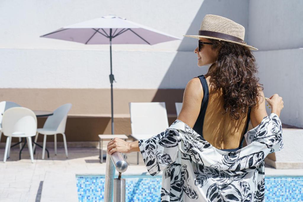 a woman wearing a hat sitting next to a pool at HDA Miraflores in Termas de Río Hondo