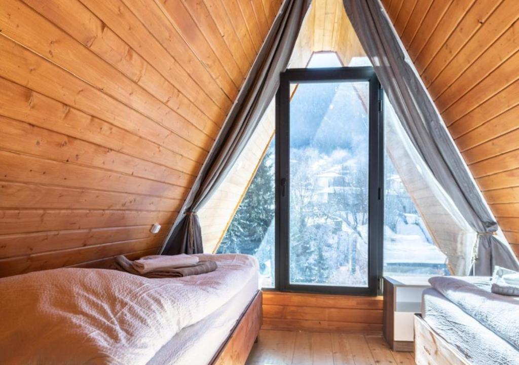 a bedroom with a large window in a wooden house at Rock Cabins Svaneti in Mestia
