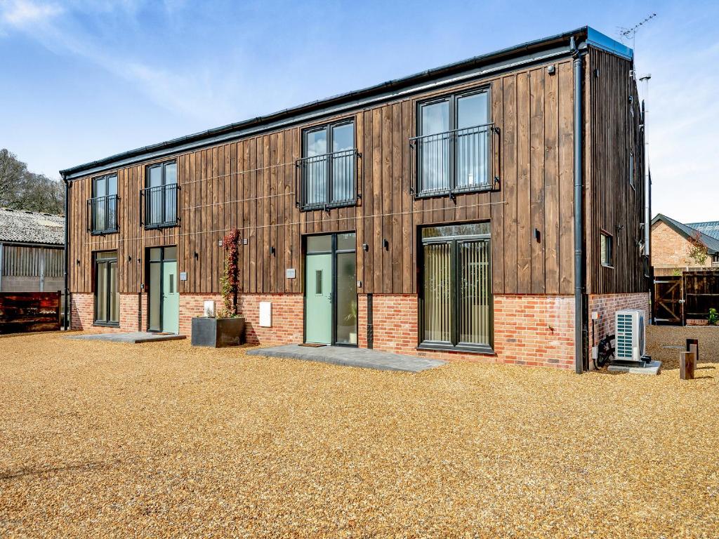 a large wooden building with doors on a gravel yard at Old Barn 2 - Uk48478 in Ferndown