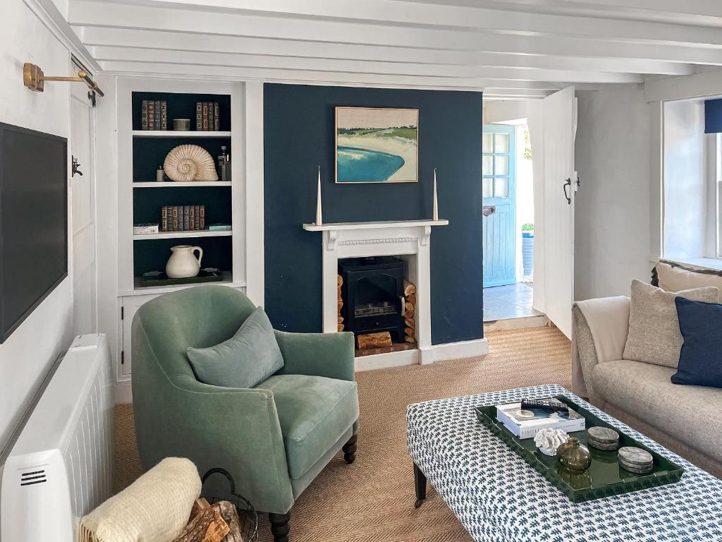 a living room with a green chair and a fireplace at Shearwaters in Saint Mawes