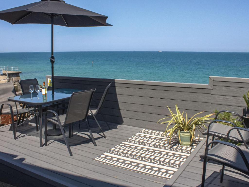 a table and chairs on a deck with the ocean at Stones Throw Cottage in Sheringham