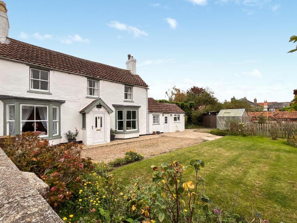 a white house with a garden in front of it at The Painters Cottage in Heckington