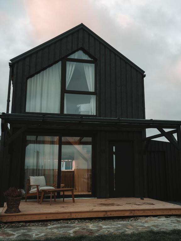 a black house with a large window on a deck at Palmera in Władysławowo
