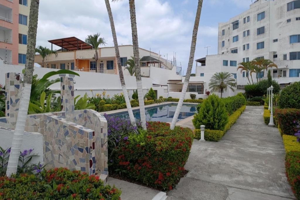 a resort with a swimming pool and palm trees at Apartamento playa Tonsupa in Tonsupa