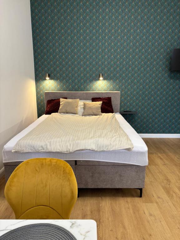 a bedroom with a bed and a yellow chair at Museum 4 Residence in Debrecen