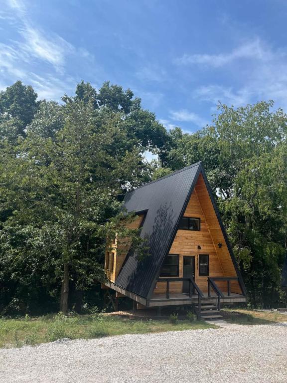 a house with a black roof and trees at Post Oak Perch-Cozy Forest A-frame Near Bentonville in Rogers