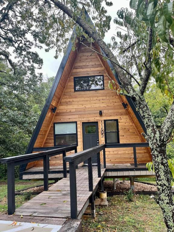 a cabin in the woods with a wooden deck at Running Spring Retreat-Cozy Forest A-Frame near Bentonville in Rogers