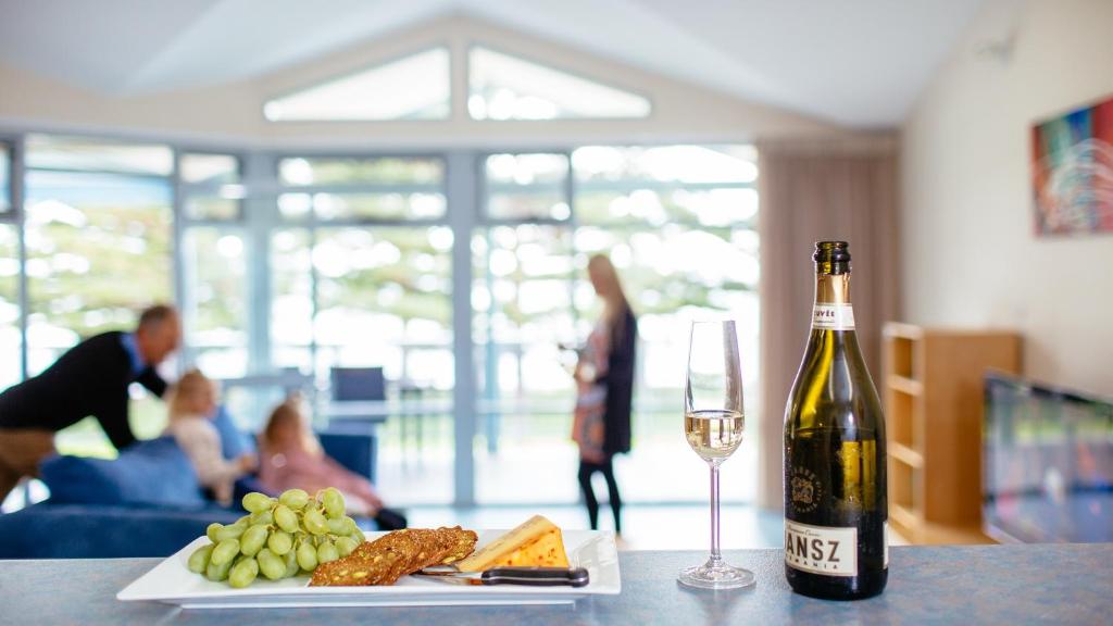 a bottle of wine and a plate of food and a glass at Port Lincoln Foreshore Apartments in Port Lincoln