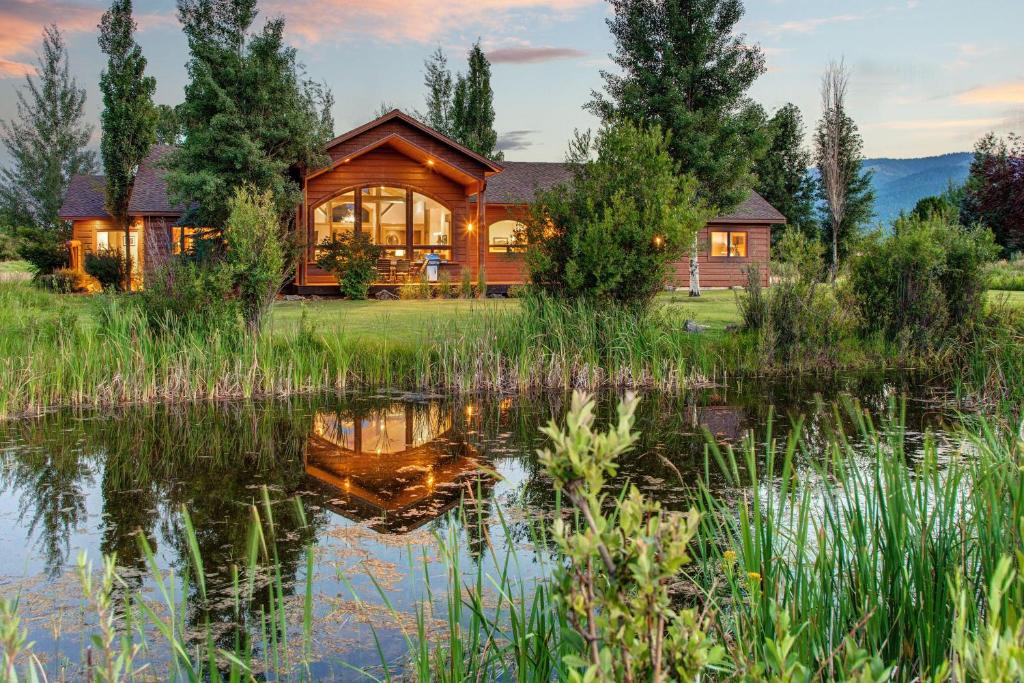 a log home with a pond in front of it at Abode at Sweetwater in Wilson