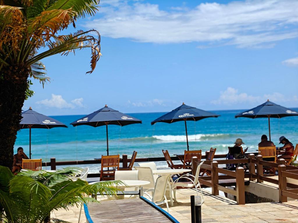 people sitting at tables with umbrellas on the beach at Pousada Porto Meu Amor in Porto De Galinhas