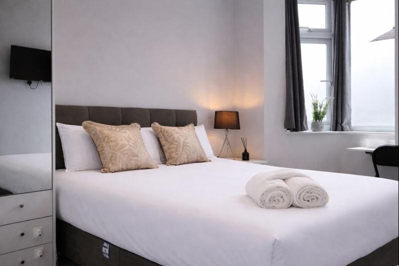 a large white bed with two towels on it at Walton Suites in Watford