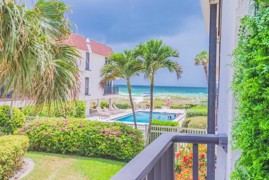 a balcony with a view of the beach and palm trees at Breezy Beachside Views! Heated Pool & Pickleball! in Holmes Beach