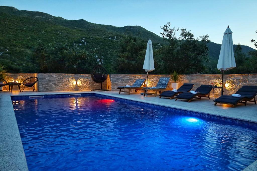 a swimming pool with lounge chairs and umbrellas at Cliffside Villa Vilić in Vrgorac