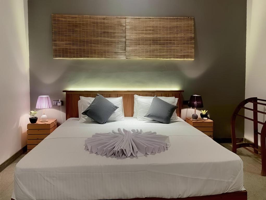 a bedroom with a large white bed with two lamps at Turtle Moon Lodge in Rekawa