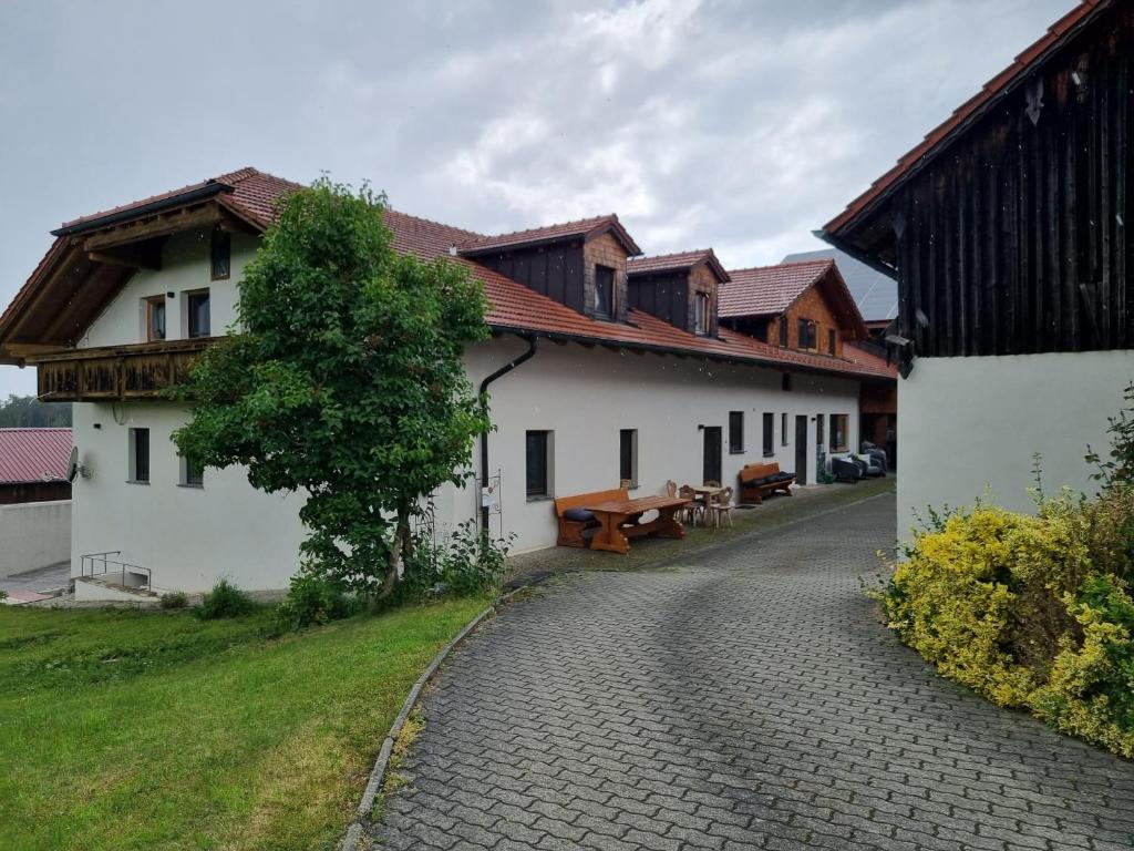 a building with a bench and a tree next to a road at Chalet Hoamad im Bayerischen Wald in Eschlkam