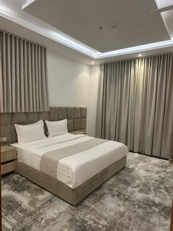 a bedroom with a large bed and curtains at جميرا محايل in Muhayil