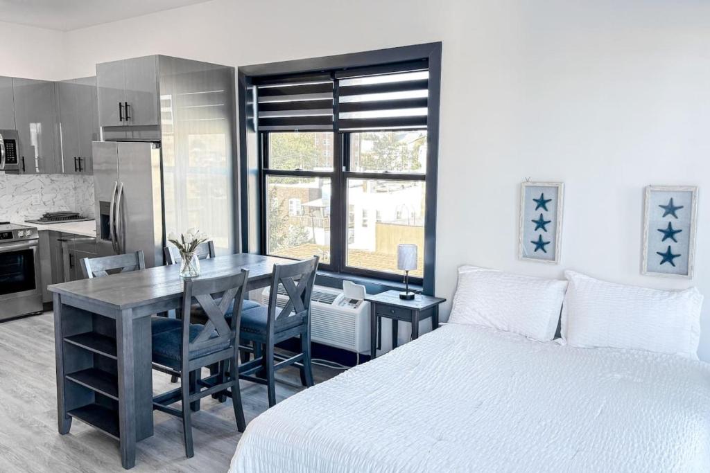 a bedroom with a bed and a table and a kitchen at Stylish Studio Apt-Outside NYC in West New York