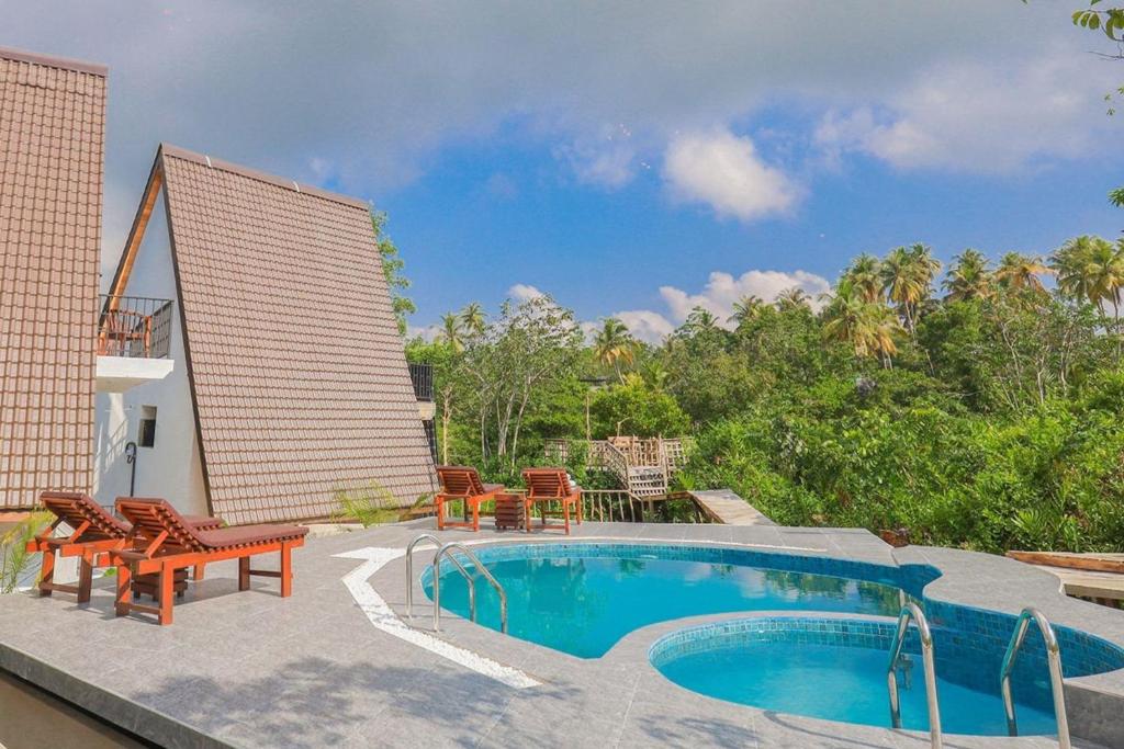 a patio with a swimming pool and chairs next to a building at The Glade in Weligama