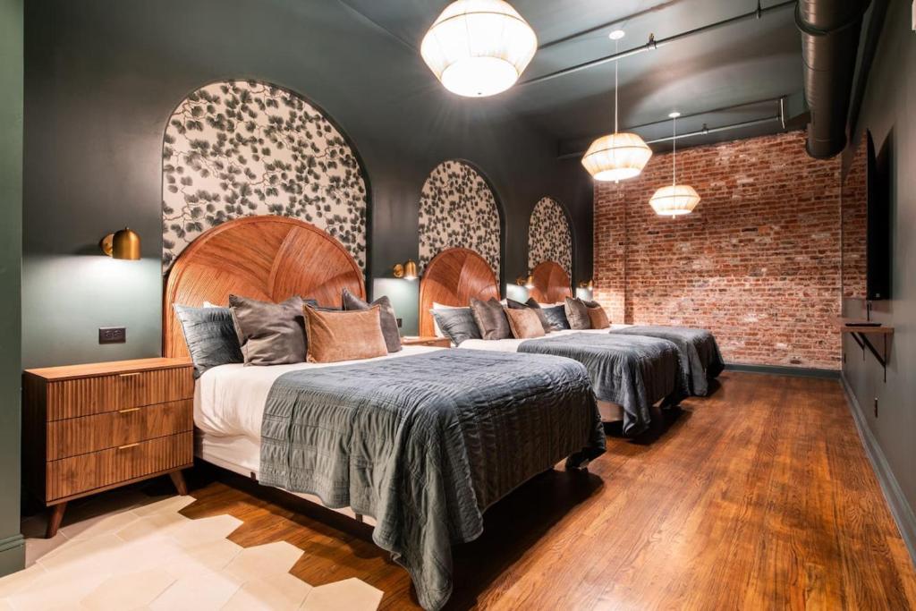 two beds in a room with brick walls at Hollyhock Suite 404 in Louisville