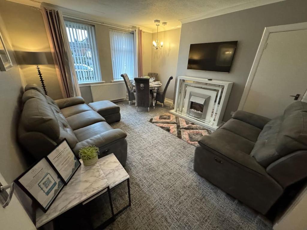 a living room with a couch and a fireplace at Modern 2BR Cottage Flat in Bellshill