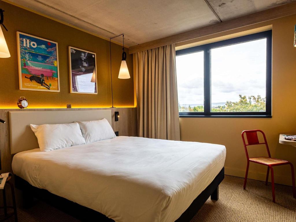 a hotel room with a large bed and a red chair at greet Hotel Reims Tinqueux in Reims