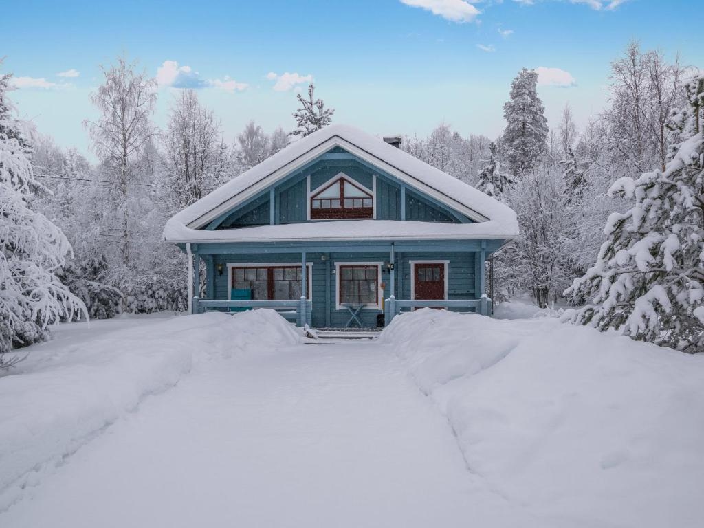 a blue house covered in snow in the woods at Holiday Home Lehtotuvat e by Interhome in Kotila