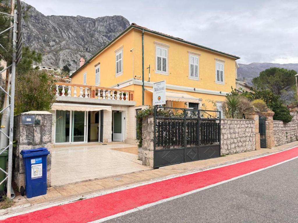a yellow house with a gate on the side of a street at Miramare Seaside Aparts in Kotor
