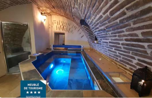 a swimming pool in a building with a brick wall at Studio et spa privatif Le Puits de la Grâce in Albi