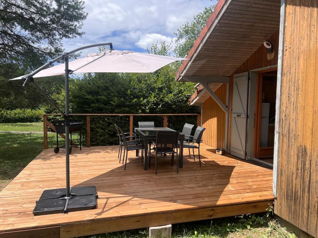 a wooden deck with a table and an umbrella at CHALET Cosy in Uxelles