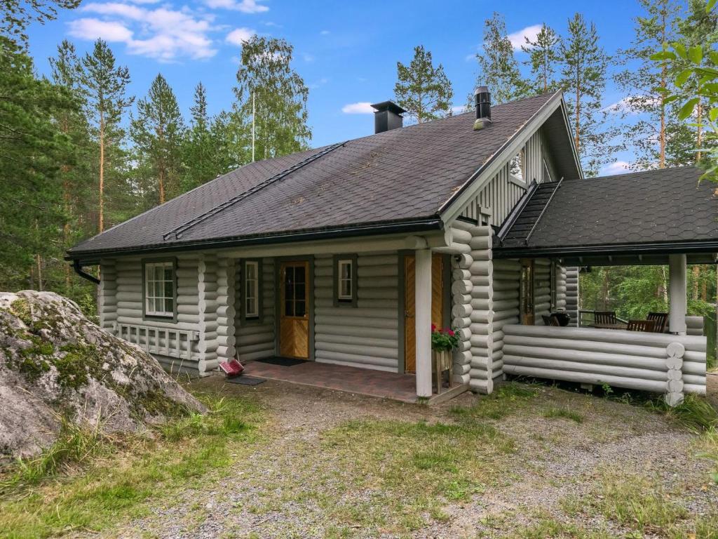 a small white cabin with a porch in the woods at Holiday Home Lahukka by Interhome in Hurissalo