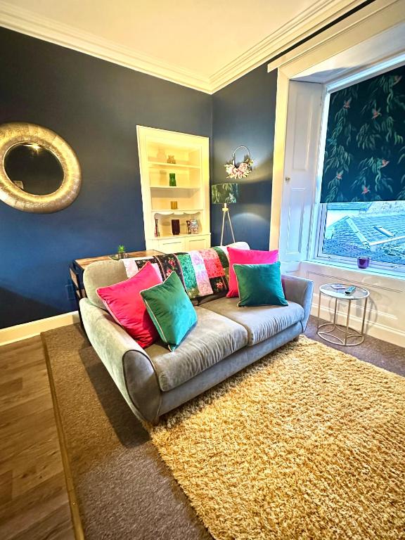 a living room with a couch with colorful pillows at Small Cosy Flat in Helensburgh