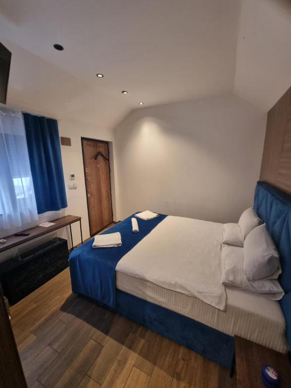 a bedroom with a large bed with a blue blanket at COni sobe Kragujevac in Kragujevac