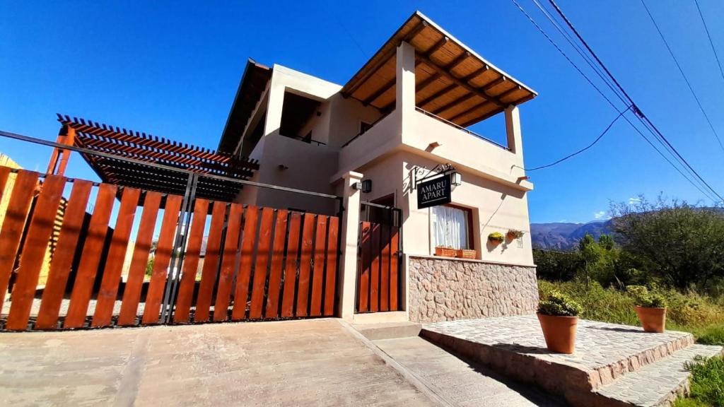a small white house with a wooden fence at Amaru Apart in Cafayate
