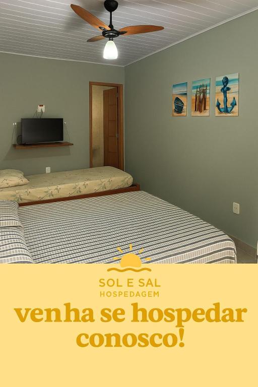 a bedroom with a bed and a ceiling fan at Sol e Sal Suítes Aconchegantes in Saquarema