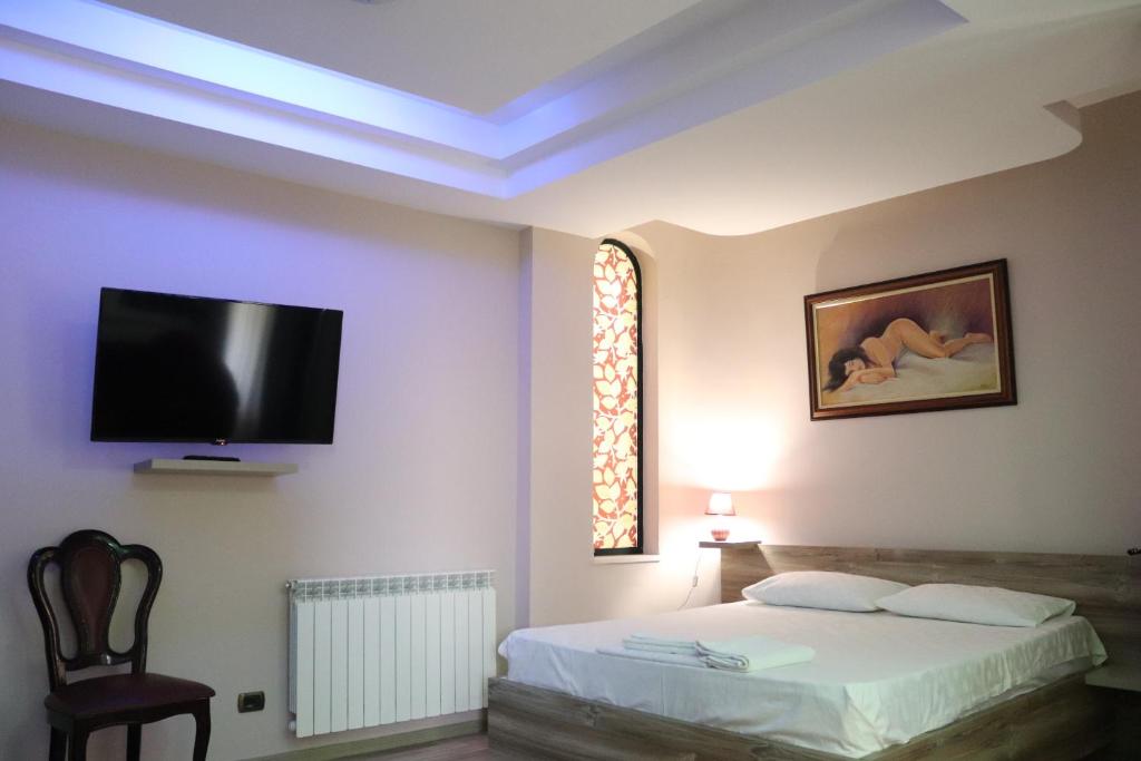 ein Schlafzimmer mit einem Bett und einem Fernseher an der Wand in der Unterkunft Hotel Sfinks Elbasan Albania in Elbasan