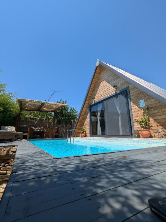 a house with a swimming pool in front of a building at Unique wooden villa with pool in Olympiada