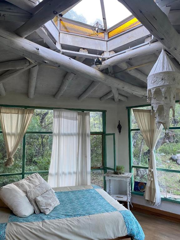 a bedroom with a bed in a room with windows at Cosmika, eco casa de montaña in Las Calles