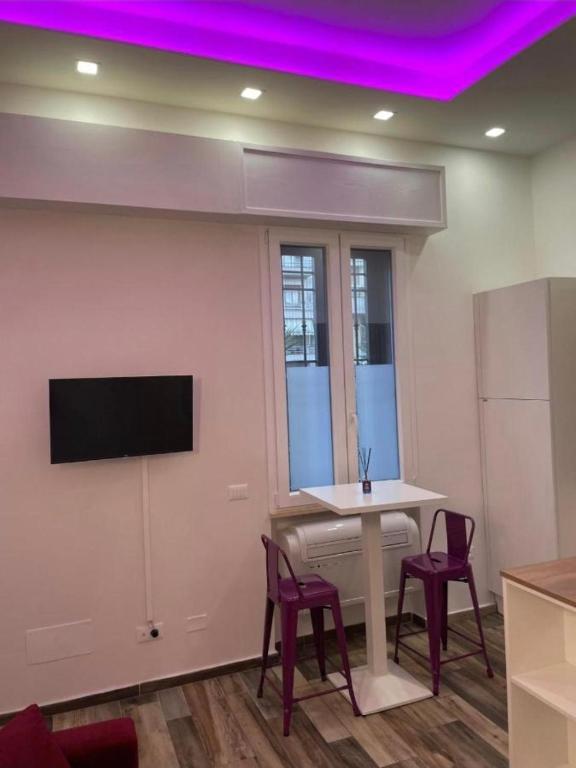 a room with a table and a tv and purple lights at Mini white apartment in Scandicci